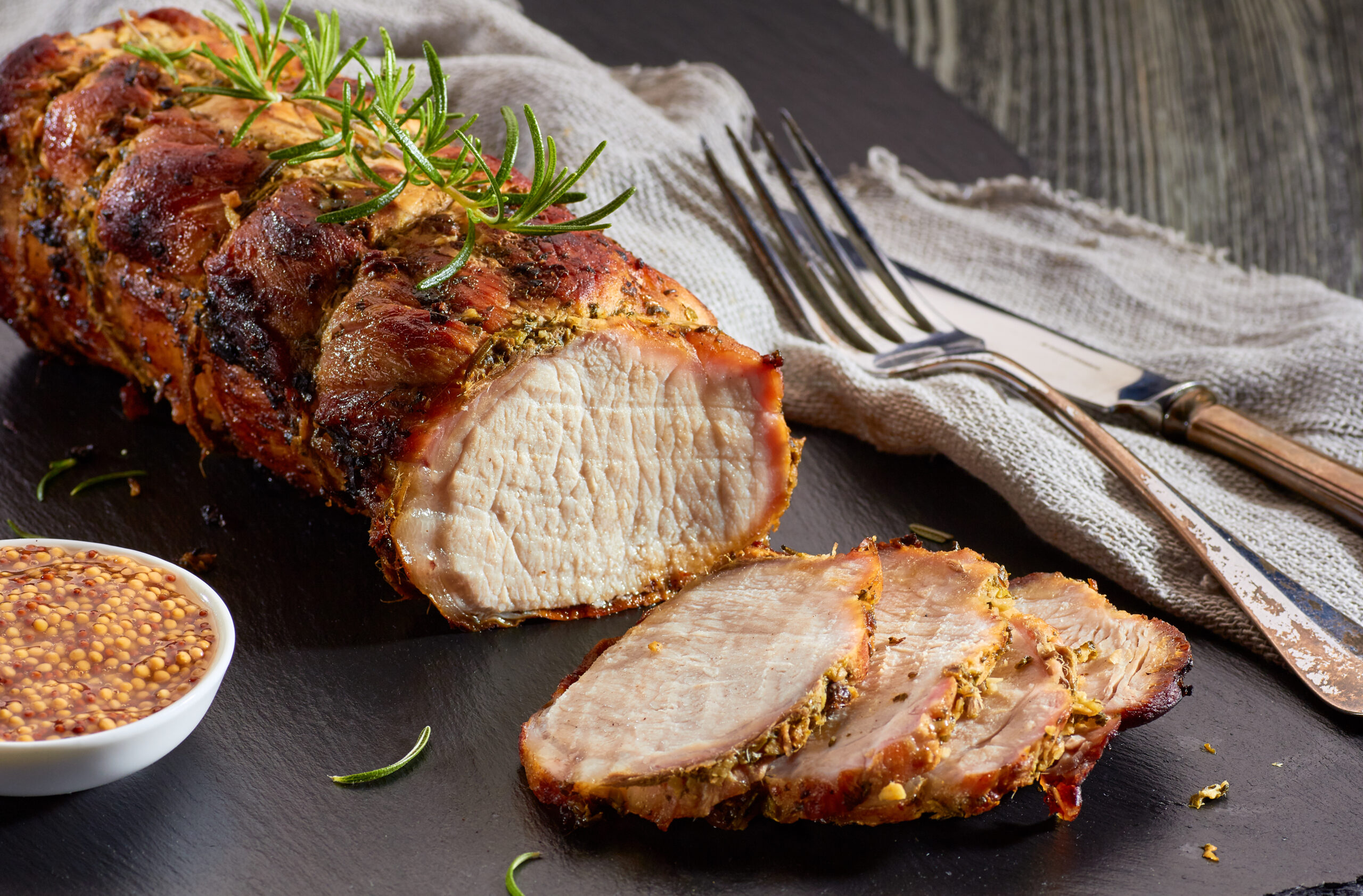 Sliced pork roast served with whole grain mustard, a delicious alternative to a pan fried pork cutlet for hearty meals.
