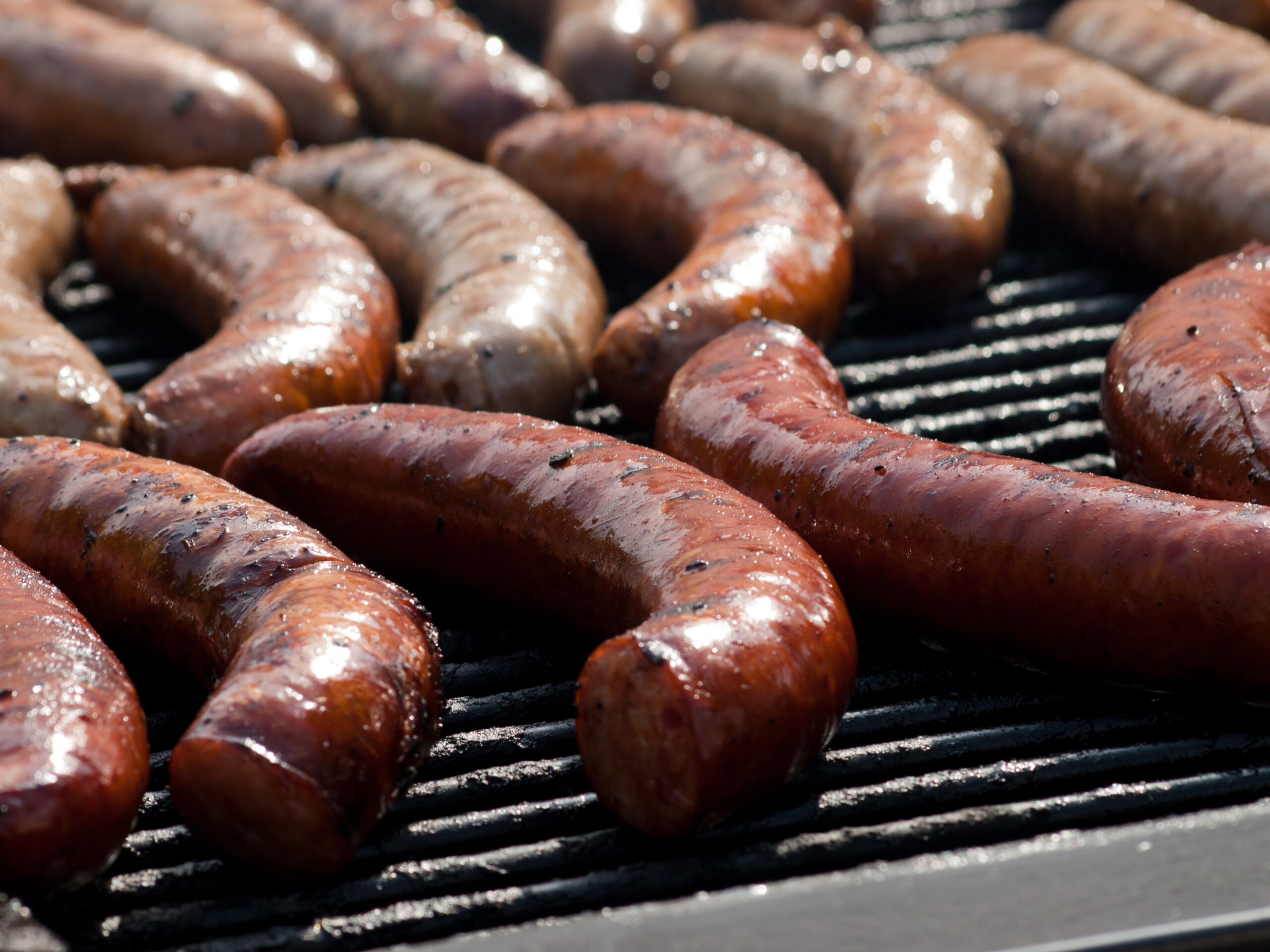 Juicy brats sizzling on a grill, illustrating cooking alternatives to baking while referencing how long to bake brats for safe internal temperature.